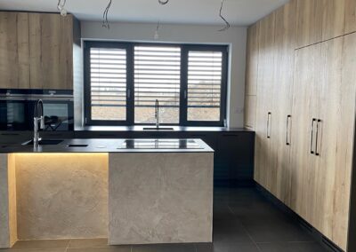 Nábytek na míru pro rodinný dům v Olomouci s ostrůvkem kombinující Fundermax a stěrku